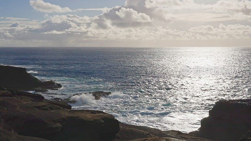 瓦胡岛的日出。白云飘过蓝天。太平洋的蓝色海浪打败了瓦胡岛火山悬崖。蓝绿色的水的颜色。晴朗的一天。DCI 4 k